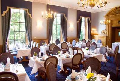 a dining room with tables and chairs and chandeliers at Royal Scots Club in Edinburgh