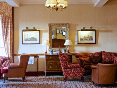 a living room with a couch and chairs and a mirror at Macdonald Crutherland House in East Kilbride