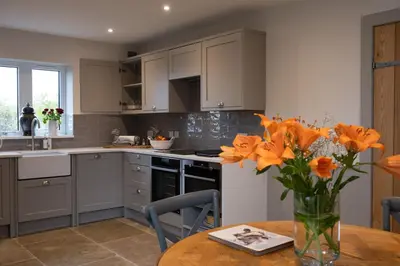 a kitchen with a table and a vase of orange flowers at Robin Cottage in Buchanty