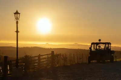 a tractor parked next to a fence at sunset at Robin Cottage in Buchanty