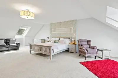 a bedroom with a bed and a chair and a red rug at Ferrypoint House in Rhu