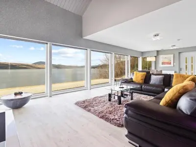 a living room with a couch and a large window at Ferrypoint House in Rhu