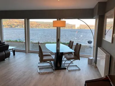 a dining room with a view of the water at Ferrypoint House in Rhu