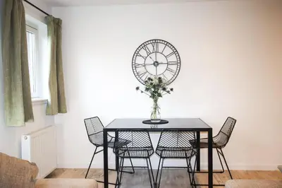 a dining room table with chairs and a clock on the wall at City Hub by the Castle Free Designated Parking in Stirling