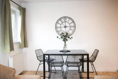 a dining room table with chairs and a clock on the wall at City Hub by the Castle Free Designated Parking in Stirling
