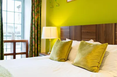 a bedroom with a bed with two yellow pillows at Lochelour Mill Cottage in Perth