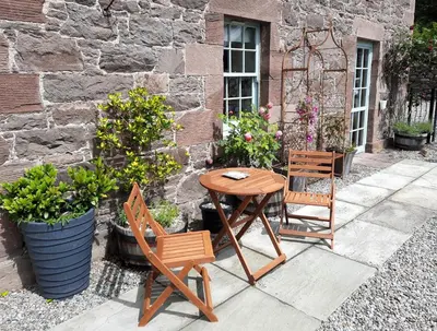 a wooden table and two chairs on a patio at Lochelour Mill Cottage in Perth