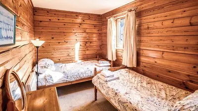 a bedroom with two beds in a wooden cabin at The New Farmhouse in Biggar
