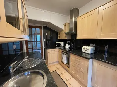 a kitchen with wooden cabinets and a sink in it at 1930s 3Bed House in Quiet Village w/ Large Garden in Bishopton