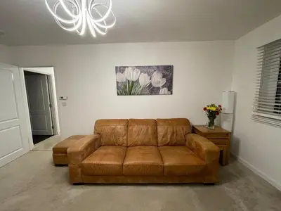a brown leather couch in a living room with a chandelier at Modern 2 Bedroom Flat in Quiet Village w/ Ensuite in Bishopton