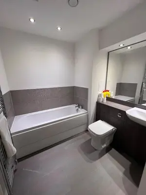 a bathroom with a tub and a toilet and a sink at Modern 2 Bedroom Flat in Quiet Village w/ Ensuite in Bishopton