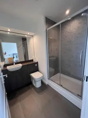 a bathroom with a shower and a toilet and a sink at Modern 2 Bedroom Flat in Quiet Village w/ Ensuite in Bishopton