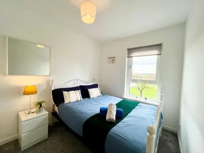 a bedroom with a blue bed and a window at Luxurious & Modern Apartment in Hawkhead