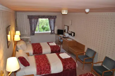 a hotel room with two beds and a desk at Willowbank Hotel in Largs