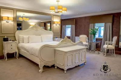 a bedroom with a large white bed with a mirror at Bowfield Hotel and Spa in Howwood