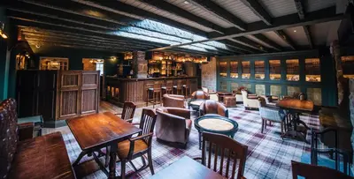 a restaurant with tables and chairs and a bar at Bowfield Hotel and Spa in Howwood