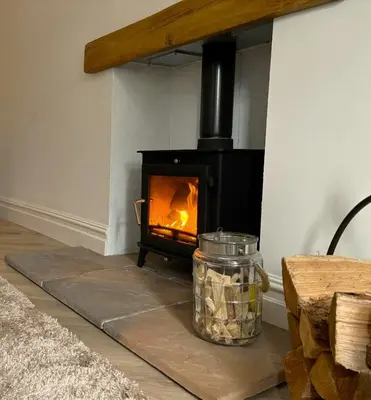 a fireplace in a living room with a glass jar at The Gate Lodge in Helensburgh