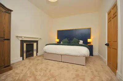 a bedroom with a large bed and a fireplace at The Gate Lodge in Helensburgh
