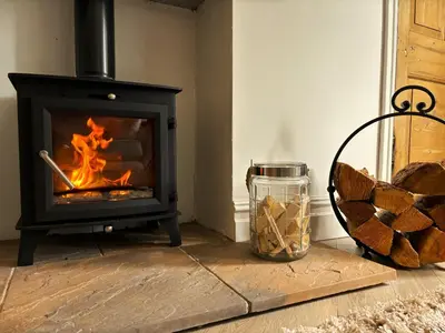 a living room with a stove with a fire at The Gate Lodge in Helensburgh