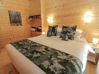 a bedroom with a large bed with wooden walls at Little Lodge in Newton Stewart
