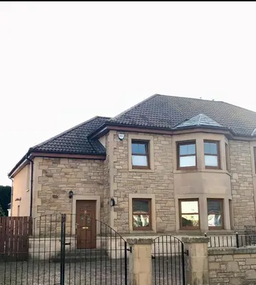a brick house with a fence in front of it at Large Modern Family Home in Murrayfield - Very close to City Centre - 10 mins by Direct Bus - Private Driveway & Garden in Edinburgh
