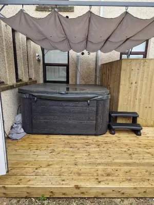 a black tub sitting on a wooden floor with a canopy at The M Rooms at 144 in Kirk of Shotts