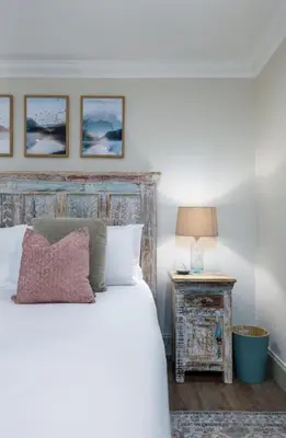 a bedroom with a bed and a table with a lamp at The Tranquil Auchterarder 3-bed Cottage in Auchterarder