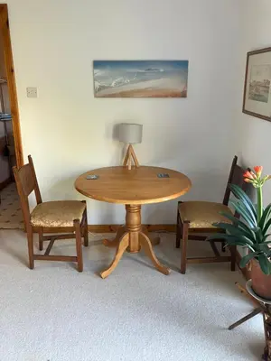 a wooden table with two chairs and a lamp at Fuaim Na Mara, The Sound Of The Sea. in Fort William