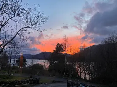 a sunset over a body of water with trees at Fuaim Na Mara, The Sound Of The Sea. in Fort William