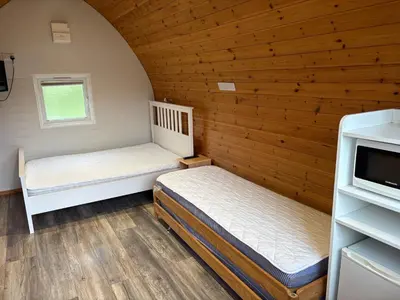 two beds in a room with wooden walls at Campsie Glen Holiday Park in Glasgow