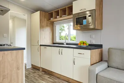 a kitchen with white cabinets and a microwave at Campsie Glen Holiday Park in Glasgow