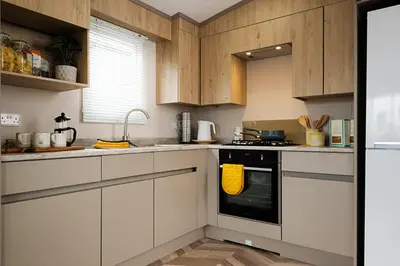 a kitchen with white cabinets and a black oven at Campsie Glen Holiday Park in Glasgow