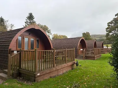 a group of cottages in a field with a fence at Campsie Glen Holiday Park in Glasgow