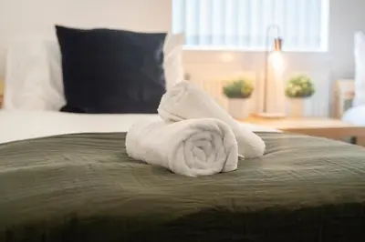 a pile of towels sitting on top of a bed at 2 Bedroom Apartment-Free Parking-by Holiday Homes in Wishaw