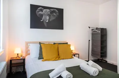 a bedroom with a bed with an elephant picture on the wall at 2 Bedroom Apartment-Free Parking-by Holiday Homes in Wishaw
