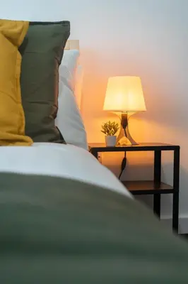 a bed with a side table with a lamp on it at 2 Bedroom Apartment-Free Parking-by Holiday Homes in Wishaw