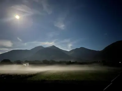 a foggy field with mountains in the background at night at View of the Mountain in North Ballachulish