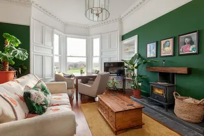 a living room with green walls and a fireplace at Beautiful Victorian Apartment close to the Botanical gardens, Free parking! in Edinburgh