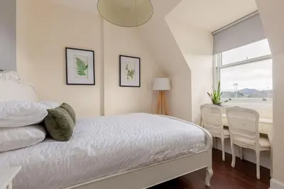 a bedroom with a bed and a table and chairs at Beautiful Victorian Apartment close to the Botanical gardens, Free parking! in Edinburgh