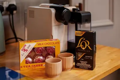 a counter with a box of muffins and a coffee maker at Beautiful Victorian Apartment close to the Botanical gardens, Free parking! in Edinburgh