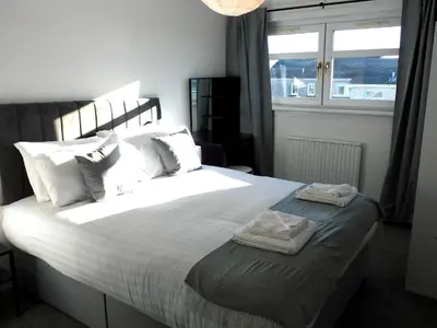 a bedroom with a large bed with two towels on it at No 54 - New & delightful 3 bed house in East Kilbride in Glasgow