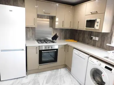 a kitchen with white cabinets and a washer and dryer at No 54 - New & delightful 3 bed house in East Kilbride in Glasgow