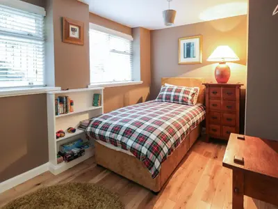a bedroom with a bed and a table and window at Lower Neuk in Dunfermline