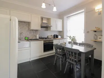 a kitchen with white cabinets and a table with chairs at Lower Neuk in Dunfermline