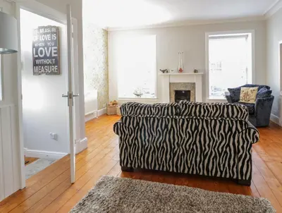 a living room with a zebra couch and a fireplace at Lower Neuk in Dunfermline