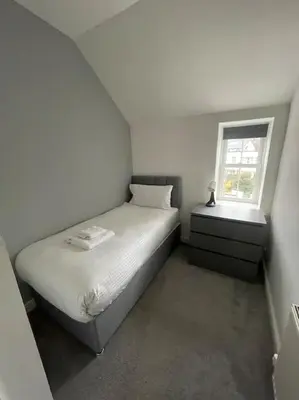 a white bedroom with a bed and a window at Carronvale. 3 Bedroom Oban Apartment. in Oban