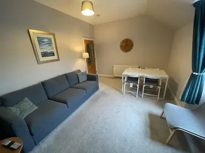 a living room with a blue couch and a table at Carronvale. 3 Bedroom Oban Apartment. in Oban