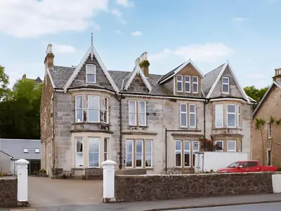 an old stone house with a red car parked in front at Island Seaview Villa in Rothesay