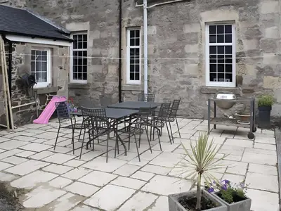 a patio with a table and chairs in front of a building at Island Seaview Villa in Rothesay