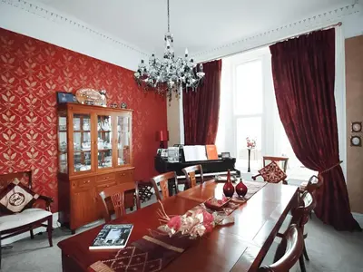 a dining room with a large wooden table and red walls at Island Seaview Villa in Rothesay